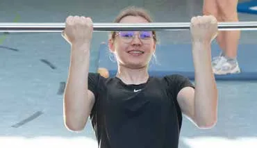Eine Schülerin hängt im Sportunterricht an einer Reckstange