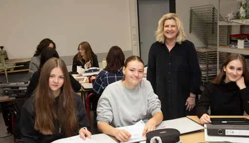 Eine Lehrerin steht lächelnd zwischen ihren Schülerinnen