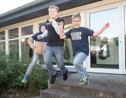 Drei Schüler springen ausgelassen eine Treppe hinunter
