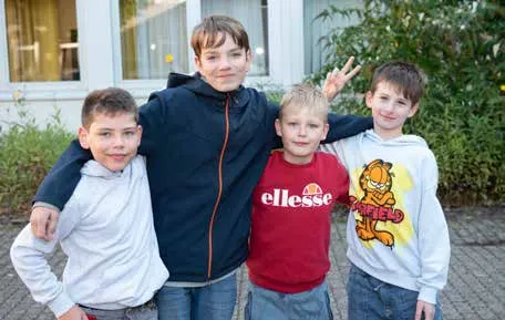 Vier Jungen stehen Arm in Arm auf dem Schulhof